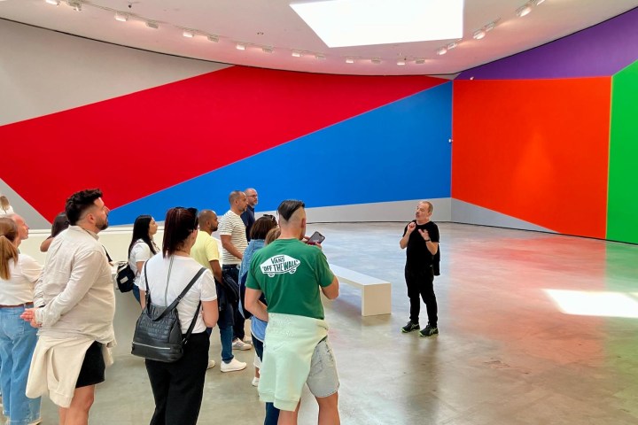People viewing colorful geometric wall art in a large gallery.