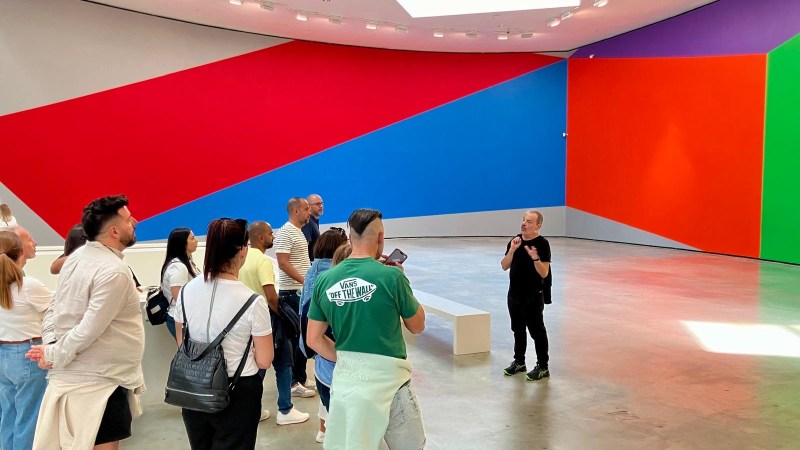 People viewing colorful geometric wall art in a large gallery.