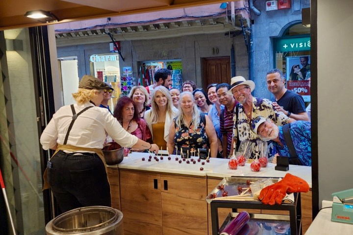 Group smiling at a candy store, with a staff member preparing candy apples.