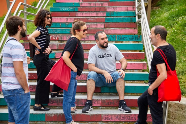 Group of five adults talking on colorful, graffiti-covered stairs.
