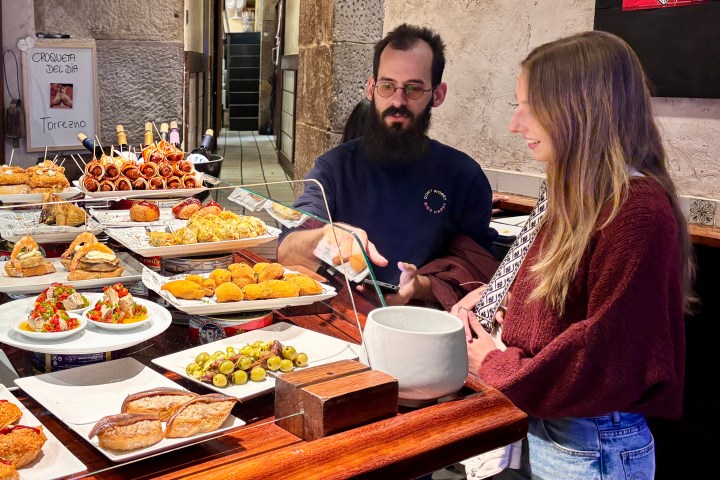 Man and woman at a tapas bar with various dishes displayed on the counter.