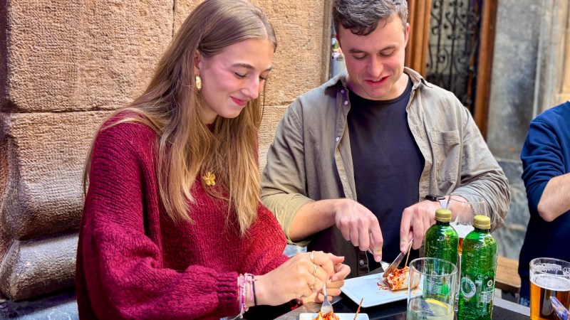 Two people enjoying a meal at an outdoor cafe with drinks on the table.