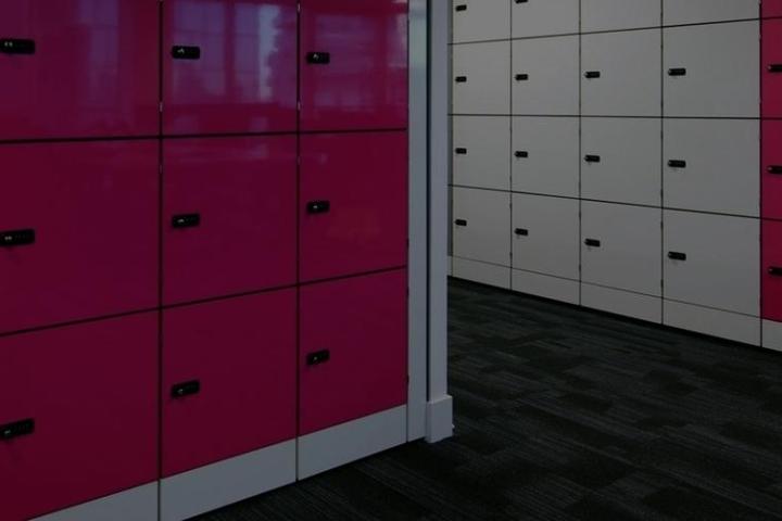 Rows of lockers with pink, gray, and white doors in a hallway.