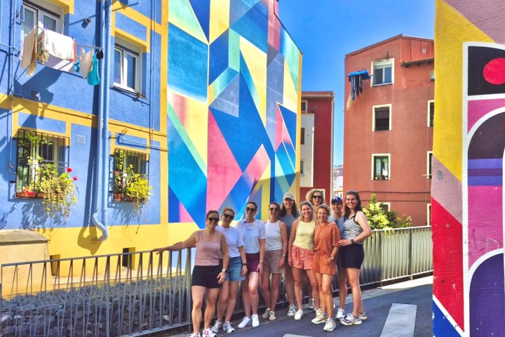 Group of people posing by colorful geometric murals on buildings.