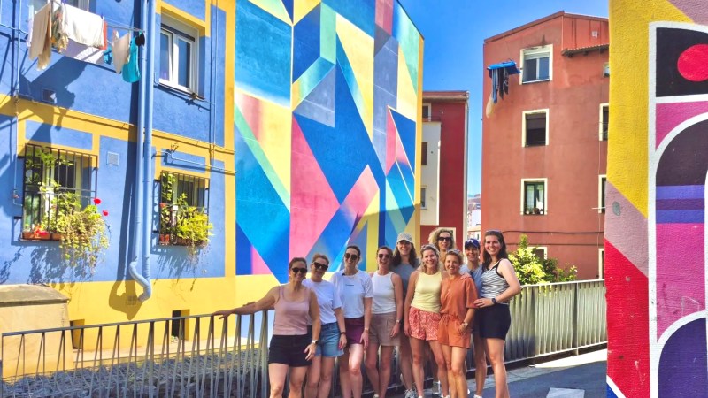 Group of people posing by colorful geometric murals on buildings.