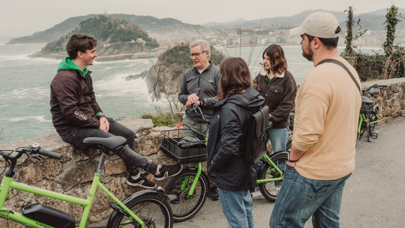 Group of people with green bikes on a coastal path with scenic view.